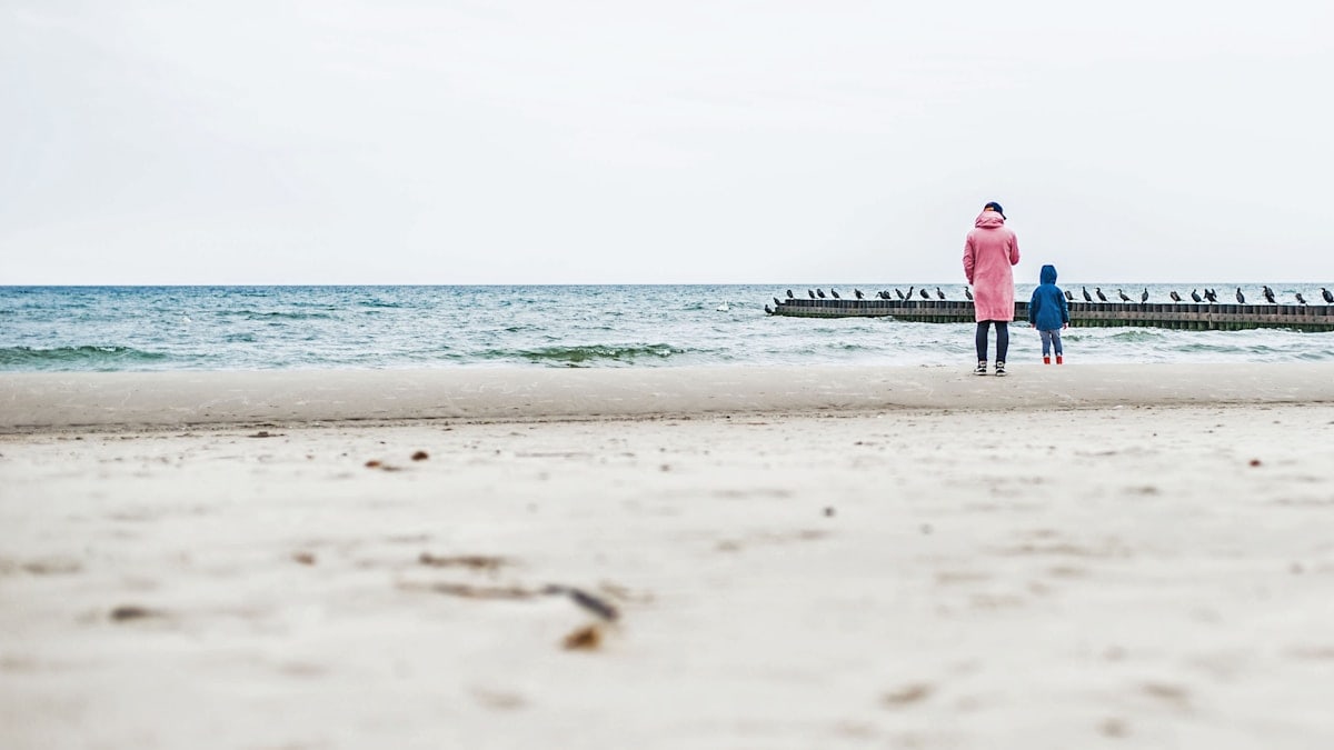 a couple of people standing on top of a sandy beach